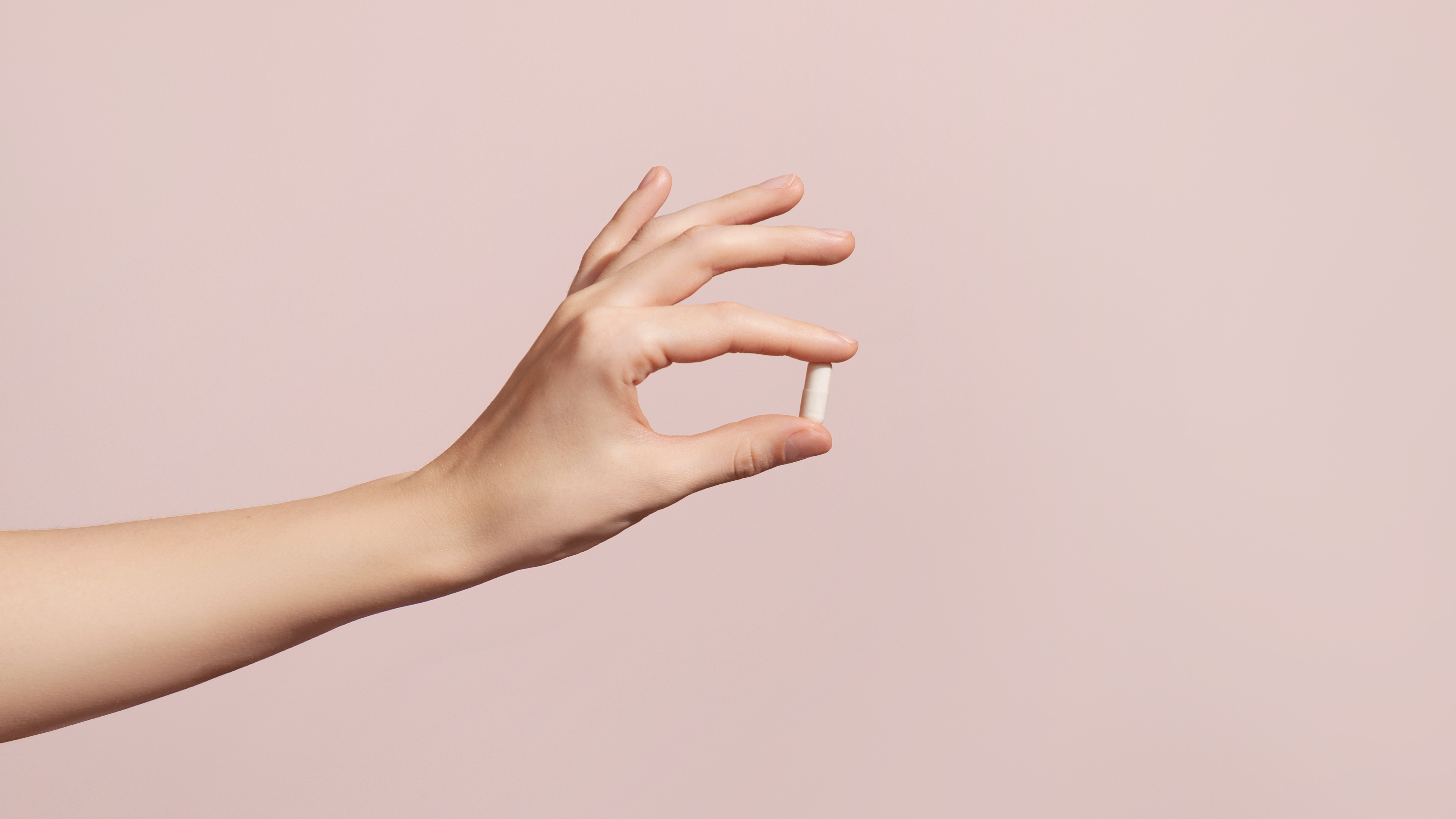 Antibiotika bei Blasenentzündung: Frauenhand hält Tablette.