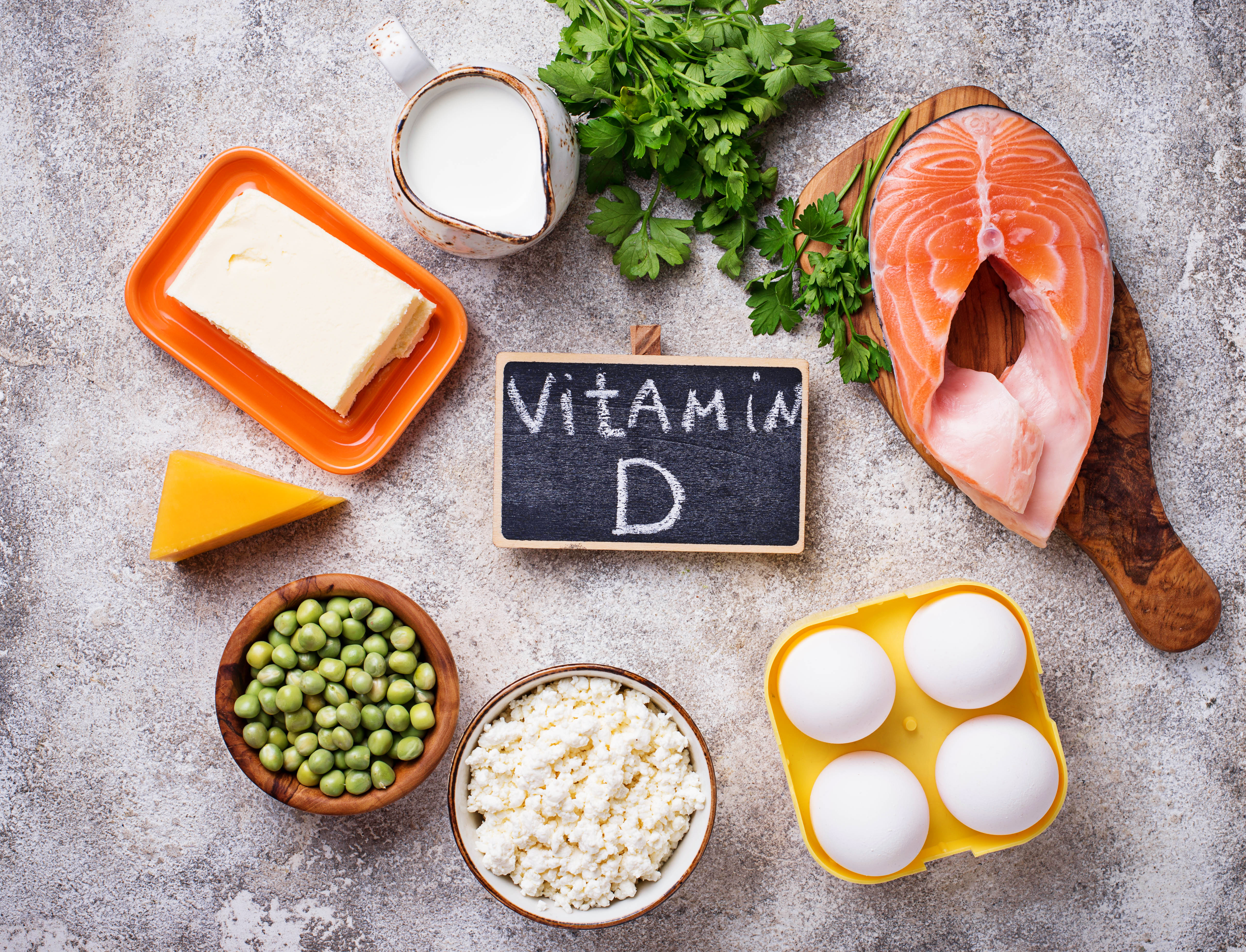 Das Bild zeigt gesunde Lebensmittel wie Lachs, Eier und Erbsen, die Vitamin D enthalten.
