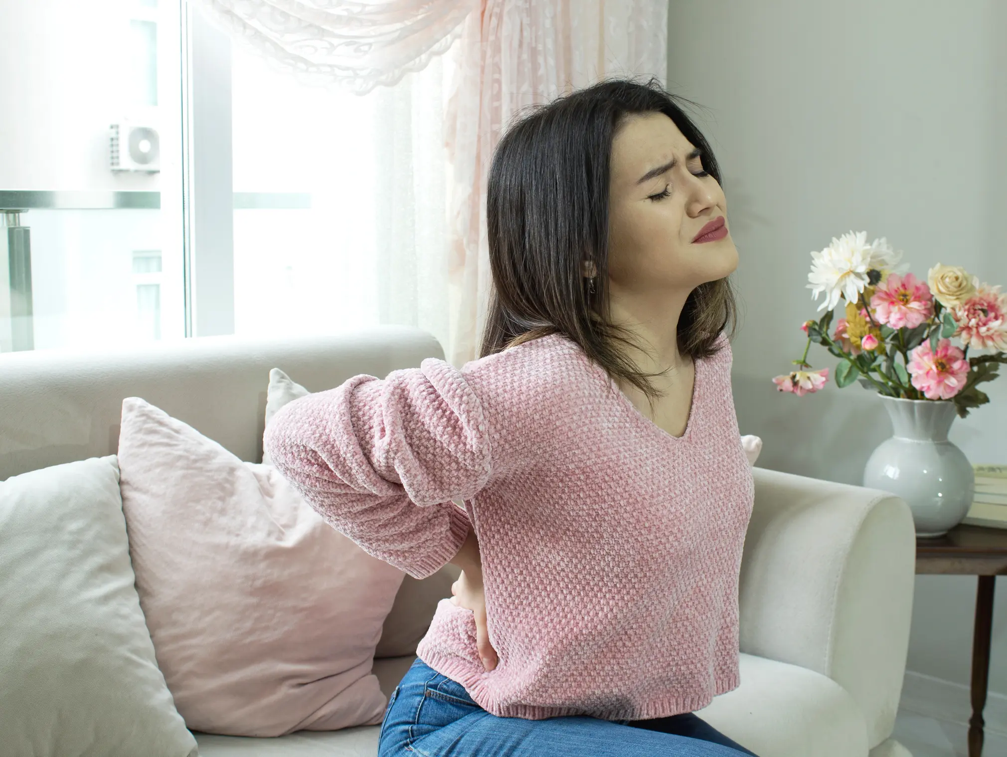 Eine Frau mit Nierengrieß hält sich vor Schmerzen den unteren Rücken.