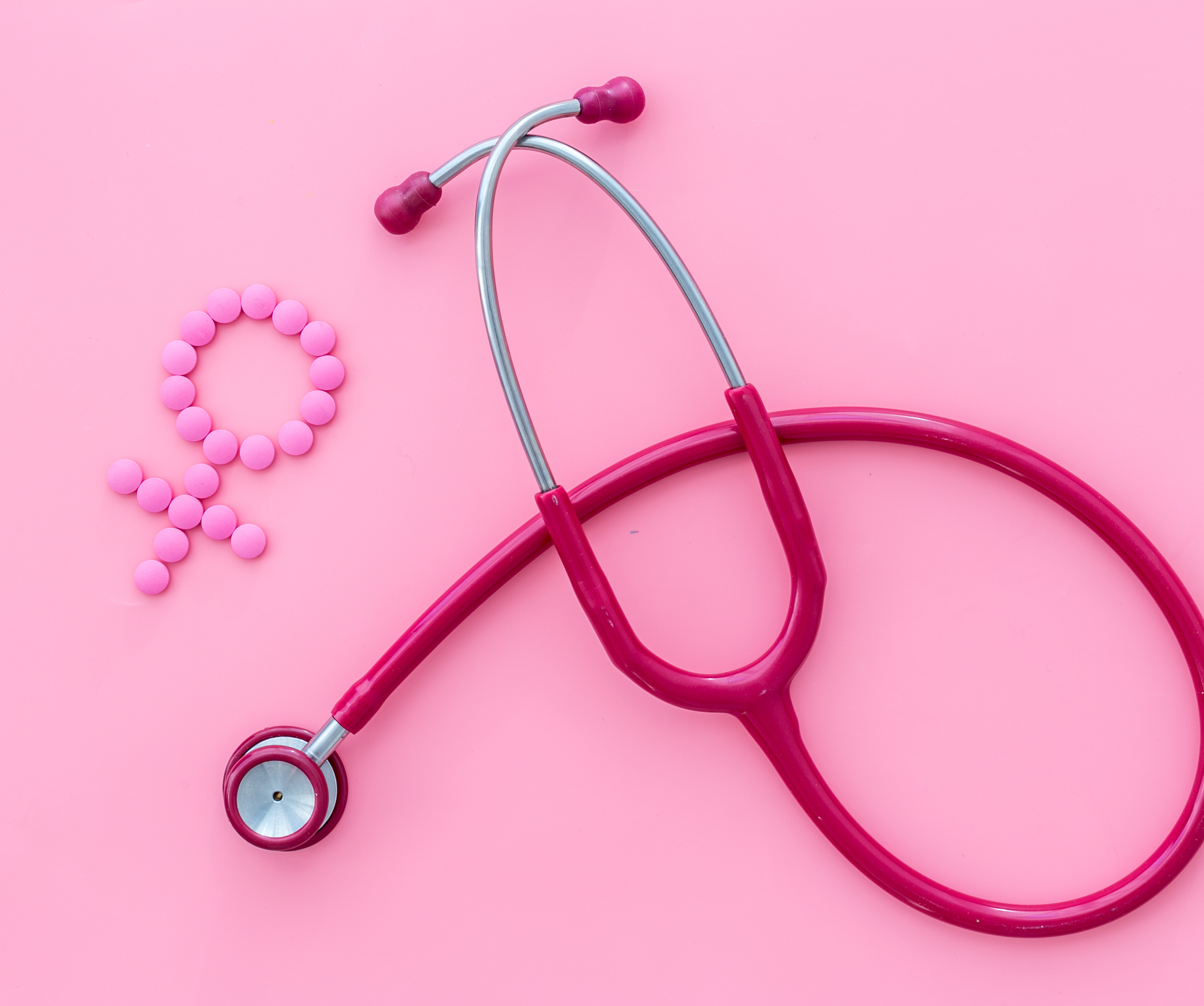 Medizinisches Konzept mit Venuszeichen und Stethoskop auf rosa Hintergrund.