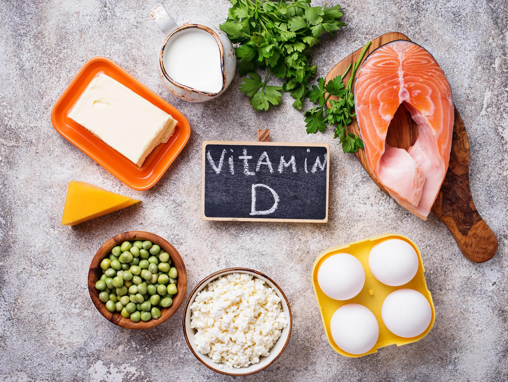 Das Bild zeigt gesunde Lebensmittel wie Lachs, Eier und Erbsen, die Vitamin D enthalten.