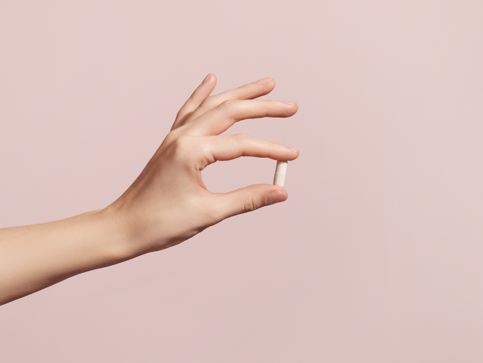 Antibiotika bei Blasenentzündung: Frauenhand hält Tablette.