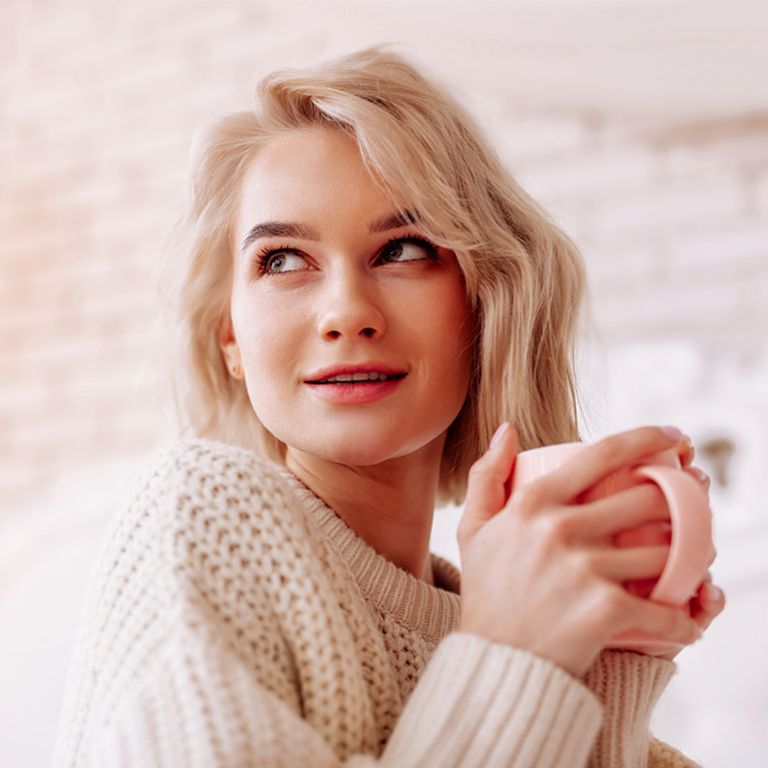 Frau mit Blasenentzündung wärmt sich an einer Tasse Tee: Viel zu trinken ist ein bewährtes Hausmittel bei Harnwegsinfekten.