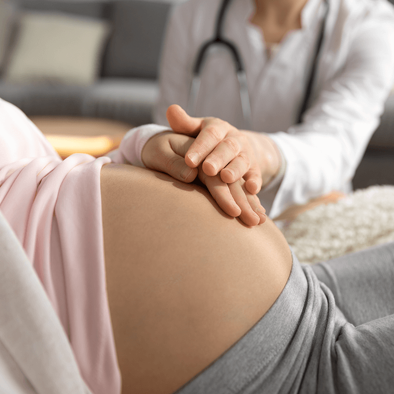 Gynäkologin legt einer Schwangeren die Händen auf den Bauch: Deuten die Beschwerden in der Schwangerschaft auf eine Blasenentzündung hin?