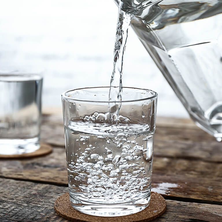 Ein Glas wird mit Wasser befüllt: Zur Vorbeugung und Behandlung von Harnsteinen ist es ratsam, viel Flüssigkeit aufzunehmen.