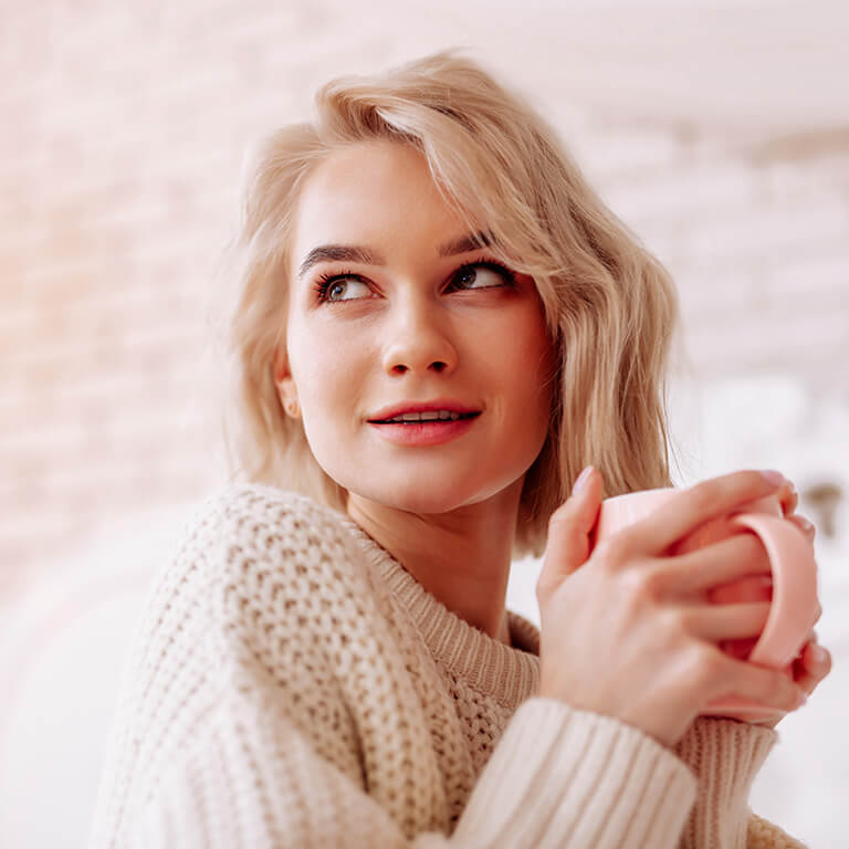 Frau mit Honeymoon-Zystitis wärmt sich an einer Tasse Tee.